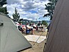 Folk sit i campingstolar mellom telt ved eit vatn.