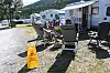 Campingvogner og bubilar på campingplass med stolar, bord og gul våtgolv-skilting.