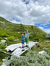 To barn står på eit vrak i fjellet under ei skya himmel.