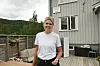Kvinne står på treterrasse ved eit bygg.