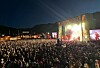 Stor folkemengd framfor lyssett scene ved fjell i skumringa.