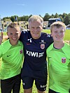 Tre fotballspelarar står saman på ein fotballbane.