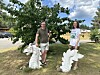 To personar står ved kvite skulpturar under eit tre i ein park.