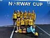 Åtte fotballspelarar i gule drakter posar framfor Norway Cup-skilt.