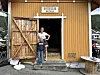 To personar står ved inngangen til eit gult bryggerhus.