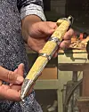 Person held ein dekorert sigarrull framfor ei diske med tobakkvarer.