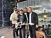 Fire musikarar står saman framfor instrument og scenelys utandørs.