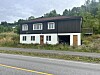 Eit hus står ved ei vegkant i eit grønt landskap.