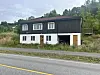 Eit hus står ved ei vegkant i eit grønt landskap.