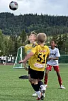 Fotballspelarar på grasbane følgjer ein ball i lufta under kamp.