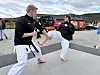 To personar utfører kampsportøving framfor raude brannbilar.