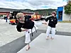 To personar øver på kampsport på matter utanfor ein brannstasjon.