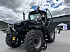 Stor traktor står utstilt på ein open plass med folk og telt i bakgrunnen.