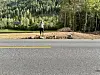 Person står ved vegkanten framfor skogkledde åsar.