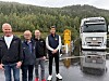 Fire menn står framfor ein kvit lastebil på ein våt arbeidsstad.