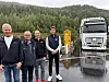 Fire menn står framfor ein kvit lastebil på ein våt arbeidsstad.
