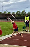 Utøvar kastar spjut på ei friidrettsbane medan ein funksjonær ser på.