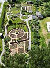 Flyfoto av ein geometrisk hage med sirkelforma bed, gangar og frodig vegetasjon.