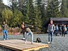 Person bøyer seg på ei treplatting medan andre står i bakgrunnen.