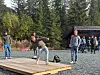 Person bøyer seg på ei treplatting medan andre står i bakgrunnen.