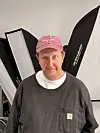 Mann med raud caps står framfor studioblitsar og reflektorar.