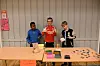Tre barn arbeider ved eit bord med fargerike aktivitetar innandørs.