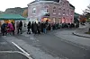 Folk står i kø utanfor ein raud murbygning.