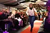 Kvinne går på raud catwalk medan publikum ser på.
